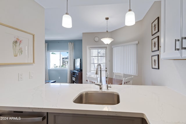 kitchen with dishwasher, light stone counters, hanging light fixtures, and sink