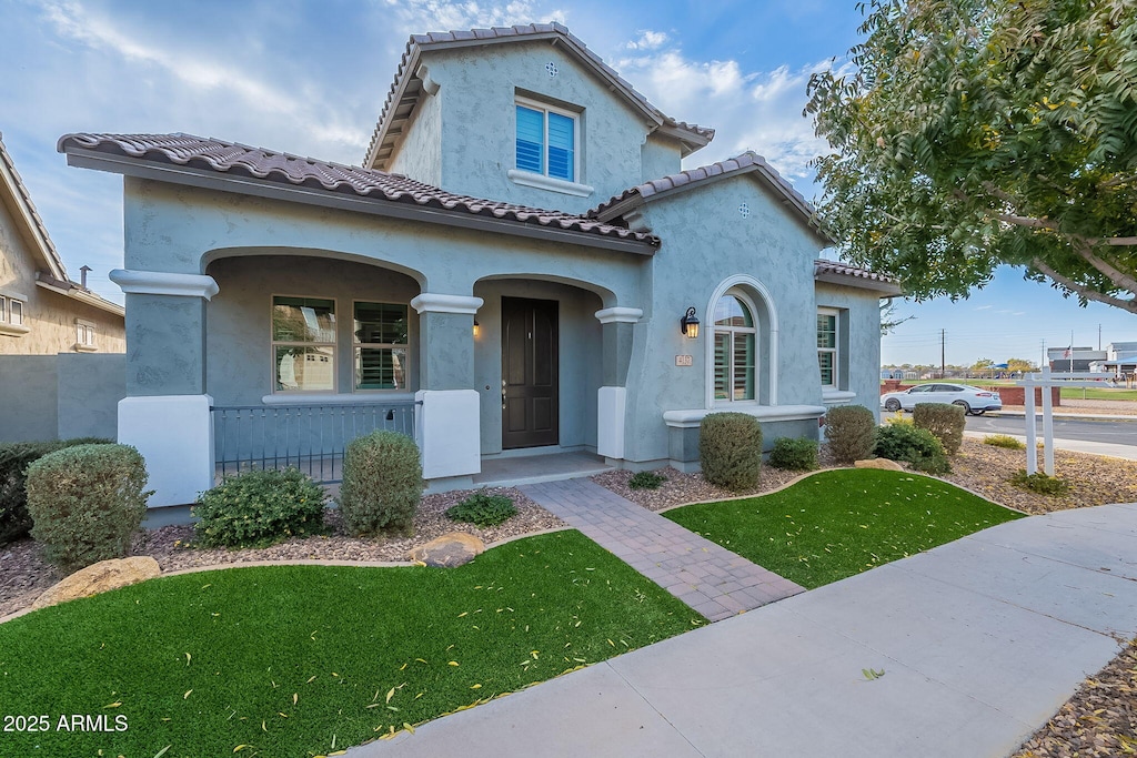 mediterranean / spanish-style home with a porch and a front lawn