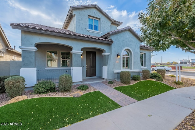 mediterranean / spanish-style home with a porch and a front lawn