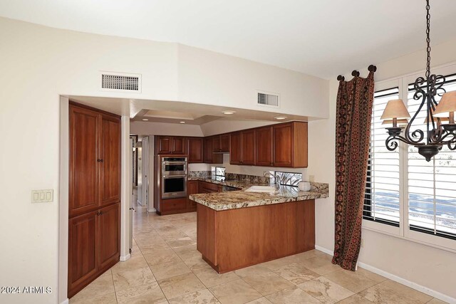 kitchen with double oven, a chandelier, kitchen peninsula, and plenty of natural light