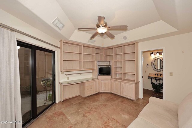 unfurnished living room featuring built in desk, ceiling fan, and a tray ceiling