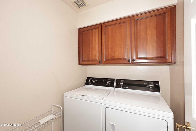 clothes washing area featuring washer and clothes dryer and cabinets