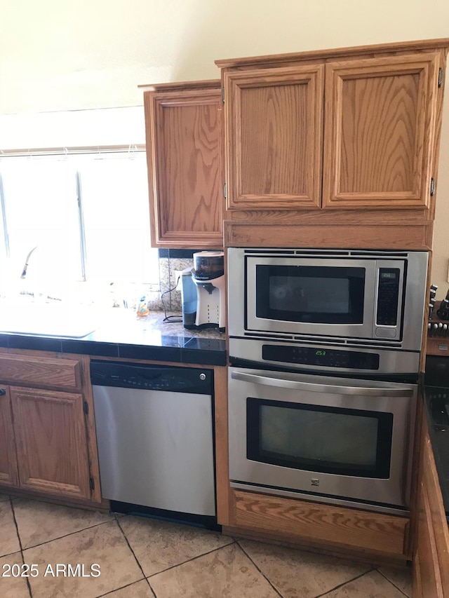 1502 E Estrid Ave, Phoenix, AZ 85022 - kitchen featuring stainless steel appliances, light tile patterned floors, and brown cabinetry