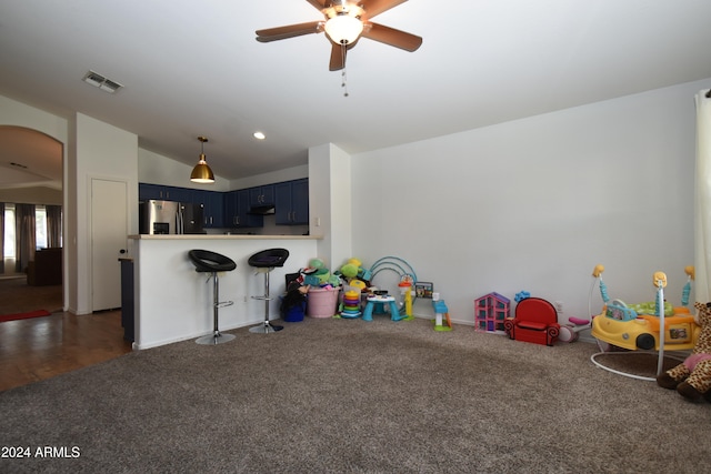 recreation room with ceiling fan, dark carpet, and lofted ceiling