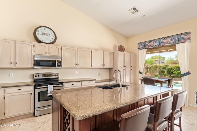 251 E Arabian Dr, Gilbert, AZ 85296 - kitchen featuring stainless steel appliances, a sink, light tile patterned floors, a kitchen bar, and light stone counters