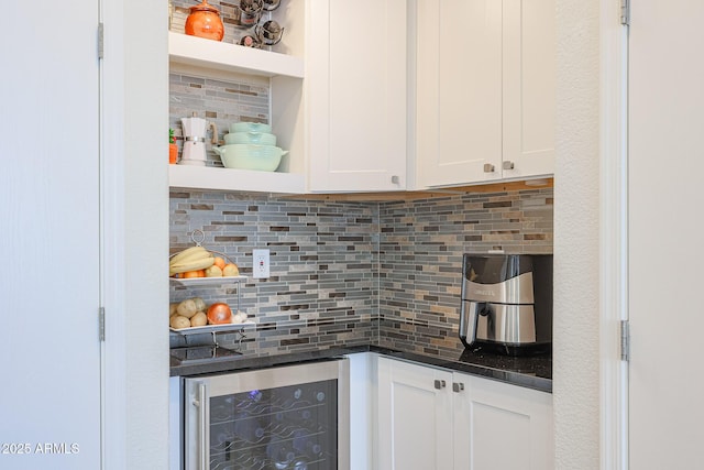 bar with wine cooler, white cabinets, decorative backsplash, and dark stone counters