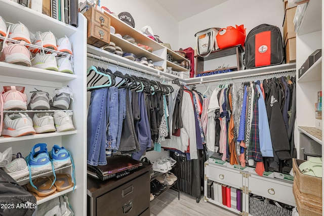 walk in closet with light hardwood / wood-style floors