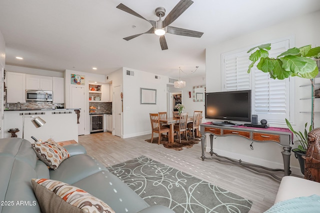 living room featuring ceiling fan, beverage cooler, and light wood-type flooring