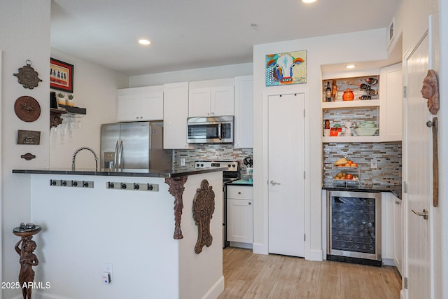 kitchen with backsplash, beverage cooler, stainless steel appliances, and white cabinetry