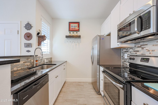 kitchen with white cabinets, stainless steel appliances, dark stone countertops, sink, and backsplash