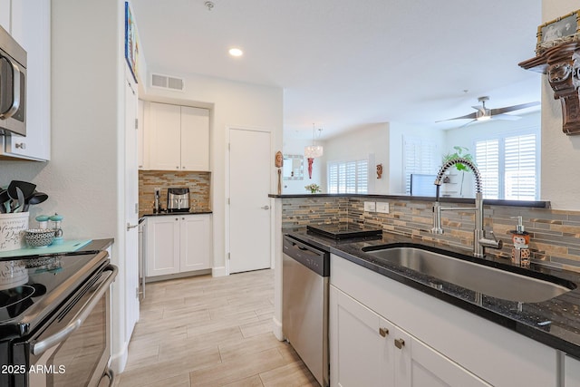 kitchen featuring ceiling fan, dark stone countertops, sink, white cabinetry, and appliances with stainless steel finishes