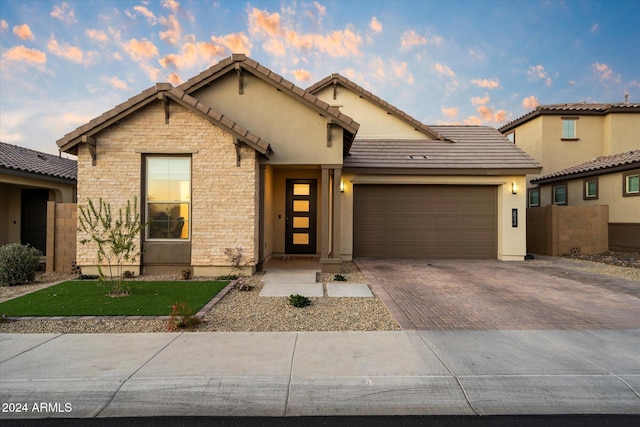 6954 W Maya Way, Peoria, AZ 85383 - view of front of house featuring a garage, decorative driveway, stone siding, and a tiled roof