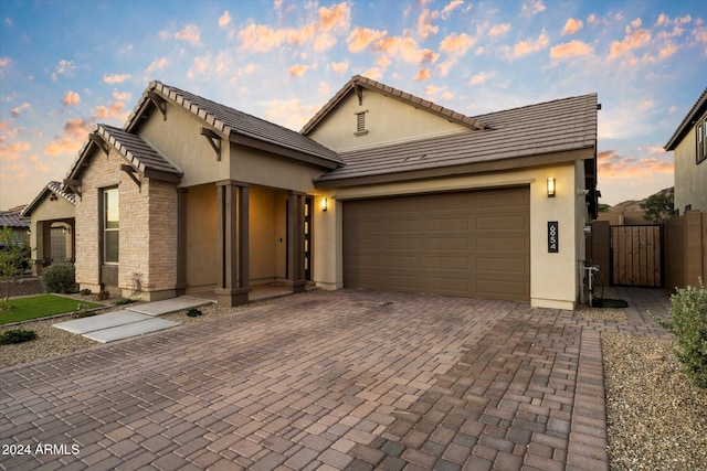 6954 W Maya Way, Peoria, AZ 85383 - view of front of property with stucco siding, decorative driveway, an attached garage, and a gate
