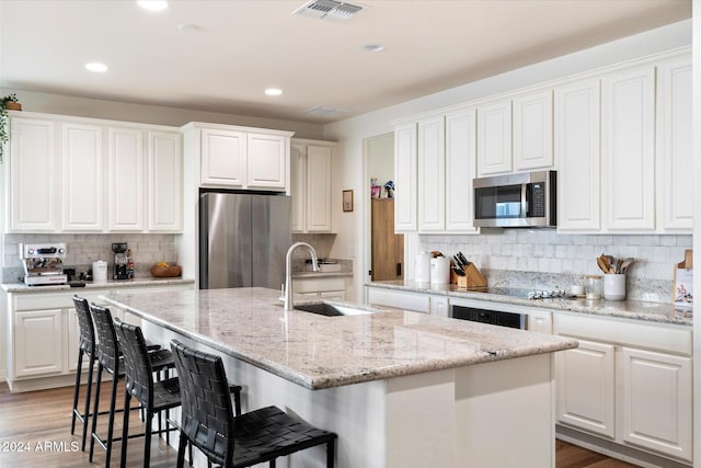 6954 W Maya Way, Peoria, AZ 85383 - kitchen with stainless steel appliances, decorative backsplash, an island with sink, light wood-style flooring, and recessed lighting