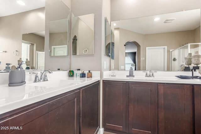 full bath with a sink, two vanities, and a stall shower