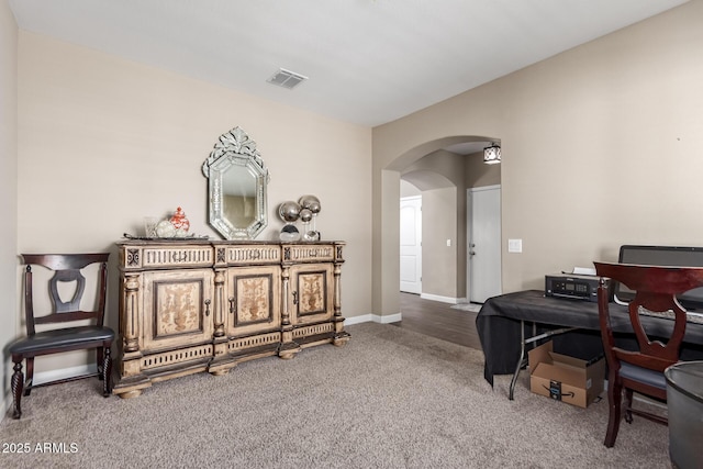 living area with arched walkways, visible vents, baseboards, and carpet floors