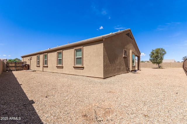 back of house with a fenced backyard and stucco siding