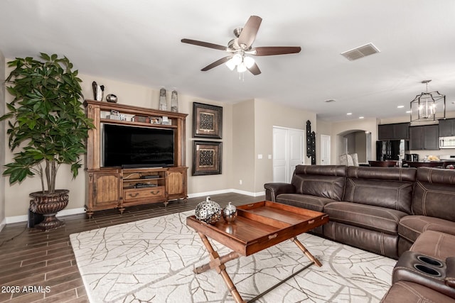 living area with baseboards, visible vents, wood tiled floor, arched walkways, and ceiling fan with notable chandelier