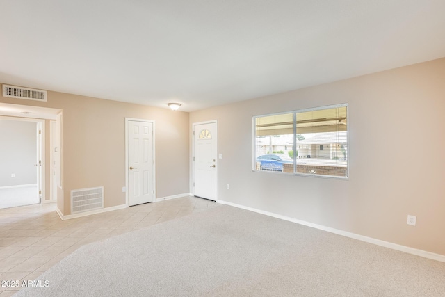 spare room featuring light tile patterned floors, baseboards, visible vents, and light colored carpet