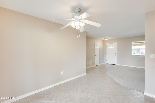 spare room with ceiling fan, light tile patterned floors, visible vents, and baseboards