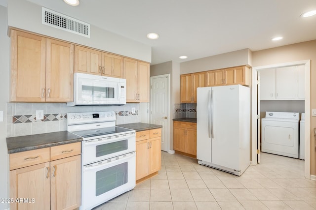 kitchen featuring dark countertops, white appliances, light brown cabinets, and washer / dryer