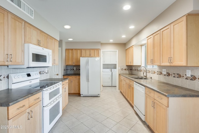 kitchen with white appliances, a sink, washing machine and clothes dryer, and light brown cabinetry