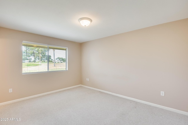 spare room featuring carpet and baseboards