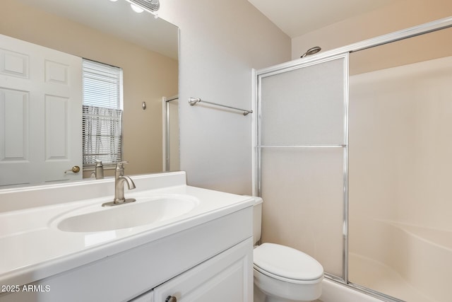 bathroom with toilet, a shower stall, and vanity