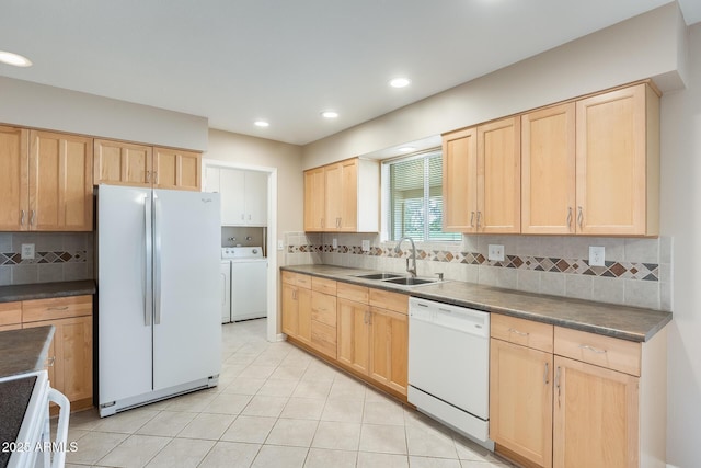 kitchen featuring decorative backsplash, light brown cabinets, a sink, washer and dryer, and white appliances