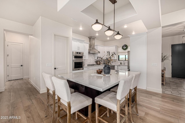 dining area featuring sink, a tray ceiling, and light hardwood / wood-style flooring