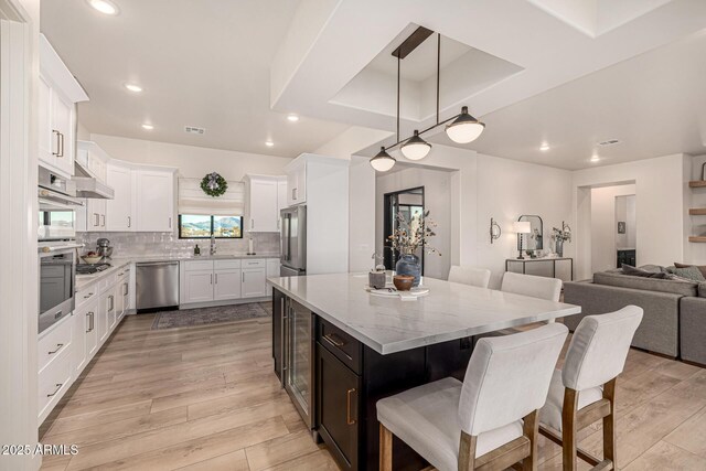 kitchen with stainless steel appliances, light hardwood / wood-style flooring, a kitchen island, and white cabinets