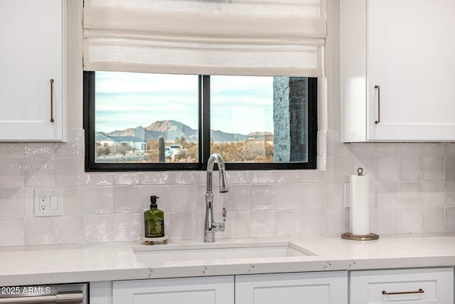 interior space featuring white cabinetry, a mountain view, backsplash, and sink