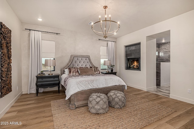 bedroom featuring a tile fireplace, hardwood / wood-style floors, and a chandelier