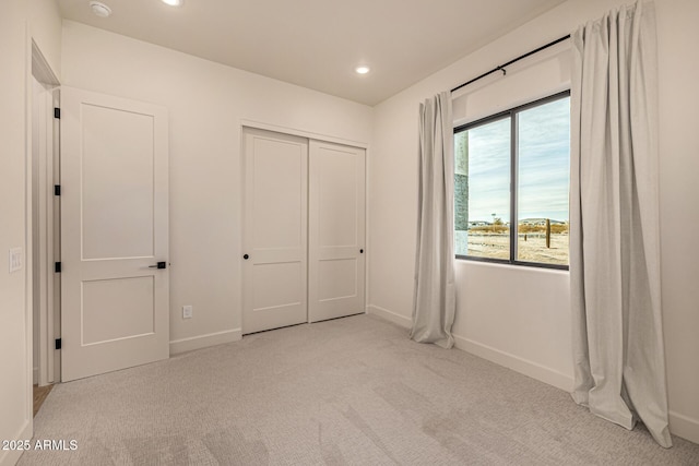 unfurnished bedroom with light carpet and a closet