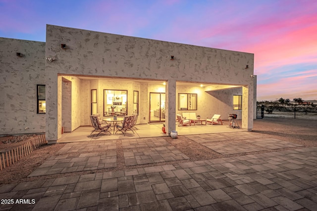 back house at dusk featuring a patio area