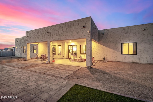 back house at dusk featuring a patio area