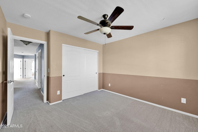 unfurnished bedroom featuring light carpet, a closet, and ceiling fan