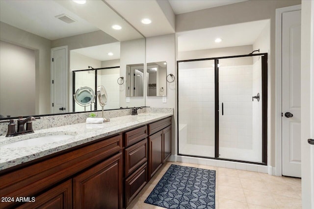 bathroom with dual sinks, tile flooring, walk in shower, and vanity with extensive cabinet space