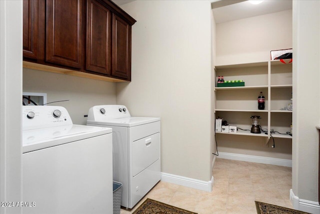 laundry area with washing machine and clothes dryer, cabinets, and light tile flooring