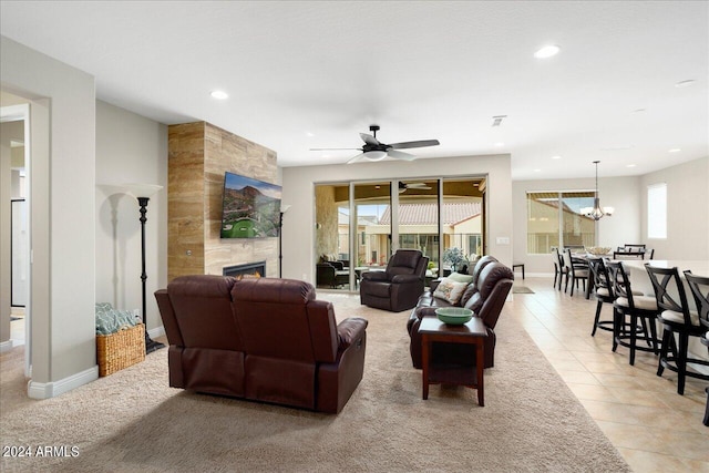 tiled living room with a large fireplace and ceiling fan with notable chandelier