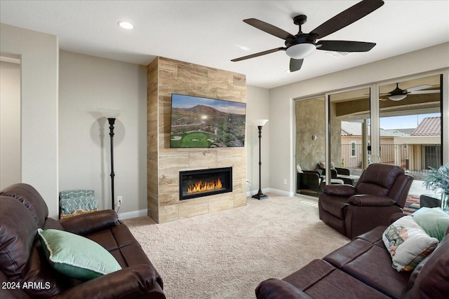 living room featuring light colored carpet, a tile fireplace, ceiling fan, and tile walls