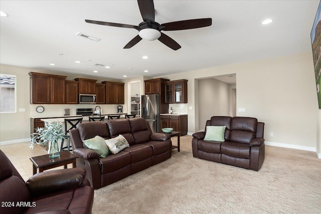 carpeted living room featuring ceiling fan and sink