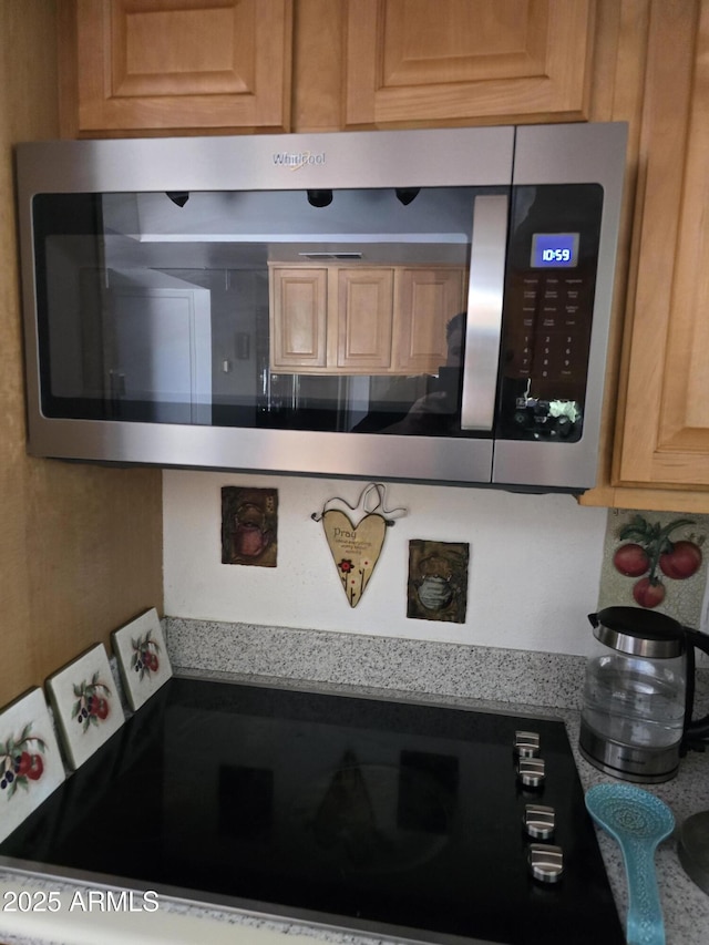 kitchen featuring light countertops, stainless steel microwave, and black electric stovetop