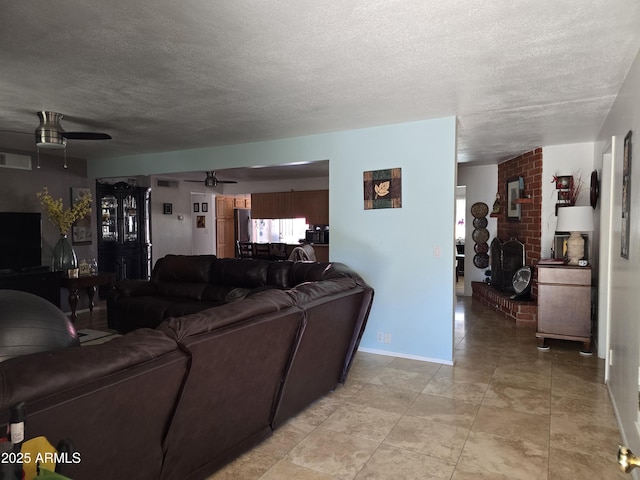 living area featuring baseboards, a ceiling fan, a textured ceiling, and visible vents