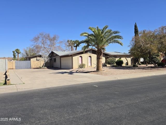 view of front of property with concrete driveway, brick siding, fence, and a garage