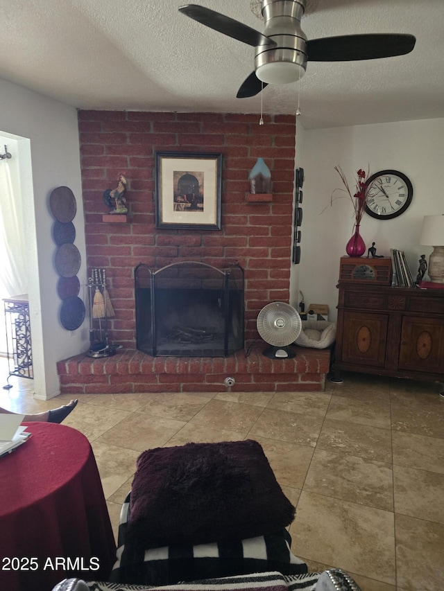 living area featuring a ceiling fan, a brick fireplace, and a textured ceiling