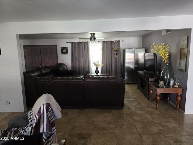 living room with a ceiling fan, baseboards, visible vents, and dark tile patterned floors