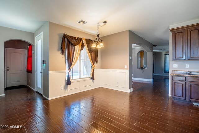 unfurnished dining area featuring dark hardwood / wood-style floors and a notable chandelier