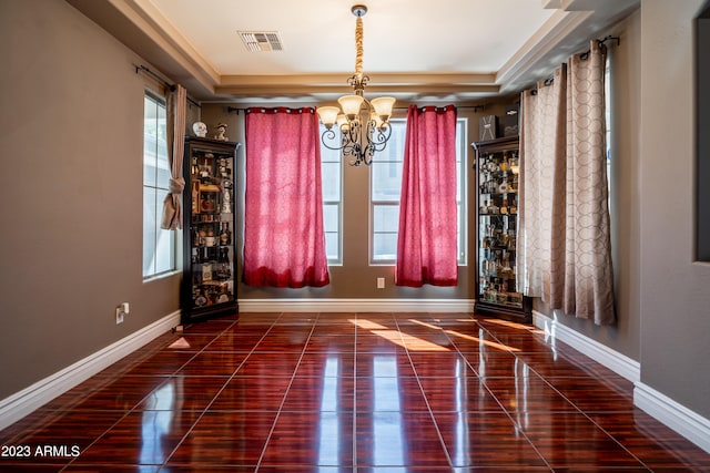 tiled spare room with a notable chandelier and a raised ceiling