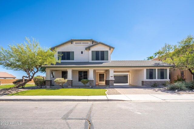 view of front of home with a garage, a front yard, and covered porch